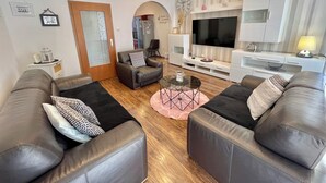 A modern living room with leather sofas, a glass coffee table, and a TV.