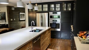 Een moderne keuken met een centraal eiland, roestvrijstalen apparatuur en houten keukenkastjes.