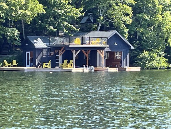 A lakeside cabin with a dock, outdoor seating, and a covered deck.