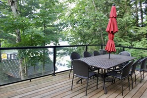 A deck with a table and chairs, overlooking a body of water.