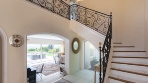 A spacious interior with a staircase, a dining area with a round table and chairs, and a view of the outdoors. - Charming 6-bedroom villa (Mouans-Sartoux)