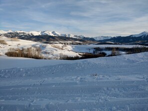 Surrounded by snow-capped mountains, this serene winter landscape offers breathtaking views of a snow-covered valley.