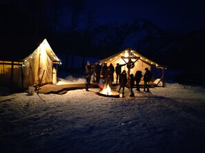 Gather around the campfire with friends and family in a serene winter wonderland setting.