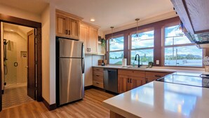 Une cuisine moderne avec des meubles en bois, des appareils électroménagers en acier inoxydable et une grande fenêtre donnant sur l’extérieur.
