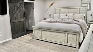 A bedroom with a bed, a dresser, a mirror, and a sliding barn-style door.