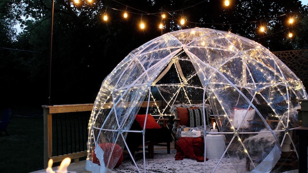 A geodesic dome structure with string lights, a table with candles, and a sign that reads "S'mores Station".