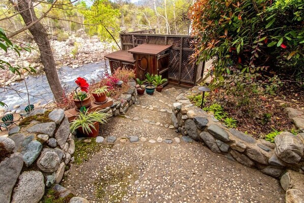 A stone pathway leading to a wooden structure with potted plants and a river in the background. - River Frontage ~ Quiet & Secluded Retreat Only Minutes to Sequoia National Park (Three Rivers)
