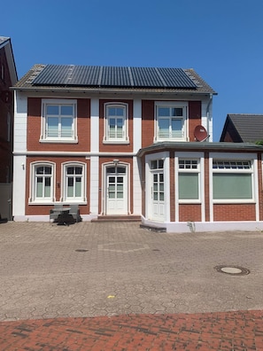 A two-story house with a garage, a satellite dish, and a paved driveway.