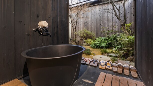 A modern bathroom with a large bathtub, a wooden door, and a small window. - Tofukuji SAKURA (Kyoto)