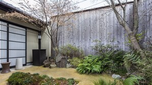 A traditional Japanese garden with a wooden fence, a stone lantern, and various plants. - Tofukuji SAKURA (Kyoto)