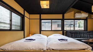A room with a bed, a black leather sofa, and a window with a view of buildings. - Tofukuji SAKURA (Kyoto)