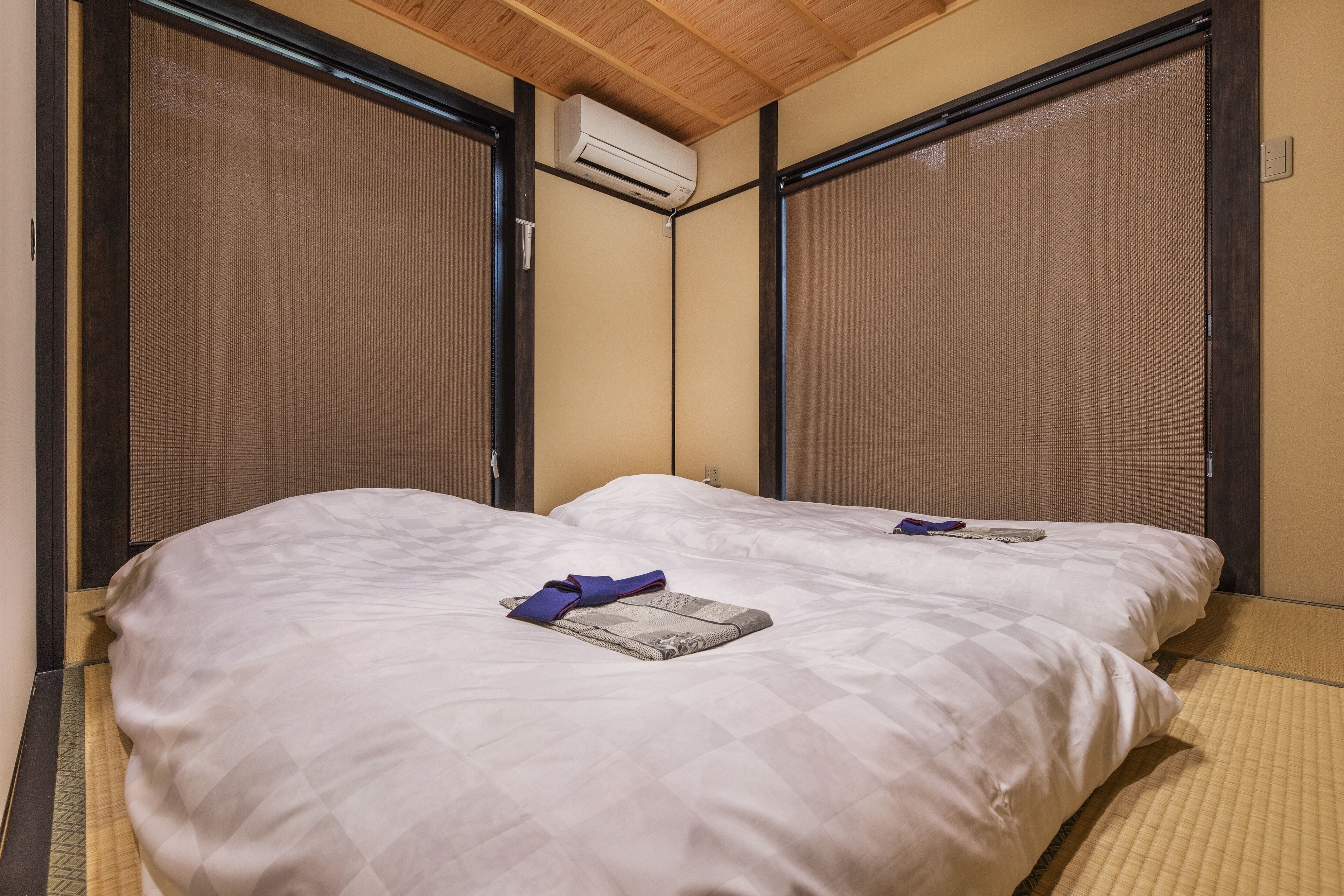 A room with two beds, a ceiling fan, and an air conditioning unit.