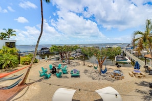 A beachside patio with lounge chairs, a hammock, and a view of the marina. - Moon Bay Condo, Paradise Found! Heated pool/marina (Key Largo)
