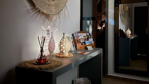 A reception area with a large woven wall hanging, a reception desk with various items, and a basket of magazines. - Charming morrocan Riad & Spa in Marrakech (MARRAKECH)