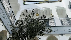 A courtyard with a tree, white walls, and a clear sky. - Charming morrocan Riad & Spa in Marrakech (MARRAKECH)