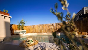 A pool area with a wooden fence, a hat on the ground, and a clear blue sky. - Charming morrocan Riad & Spa in Marrakech (MARRAKECH)