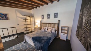 Une chambre à coucher avec un lit, des tables de chevet, une lampe et des œuvres d’art murales.