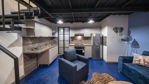 Un espace de vie compact comprenant une cuisine, un canapé et un escalier.