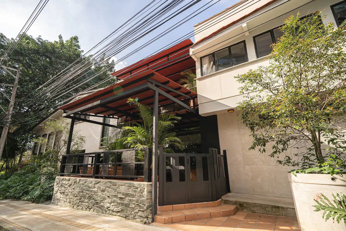 Um edifício moderno com um pátio coberto, parede de pedra e plantas em vasos.