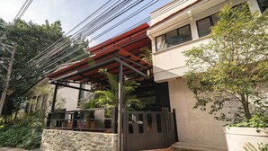 Un bâtiment moderne doté d’un patio couvert, d’un mur en pierre et de plantes en pot.