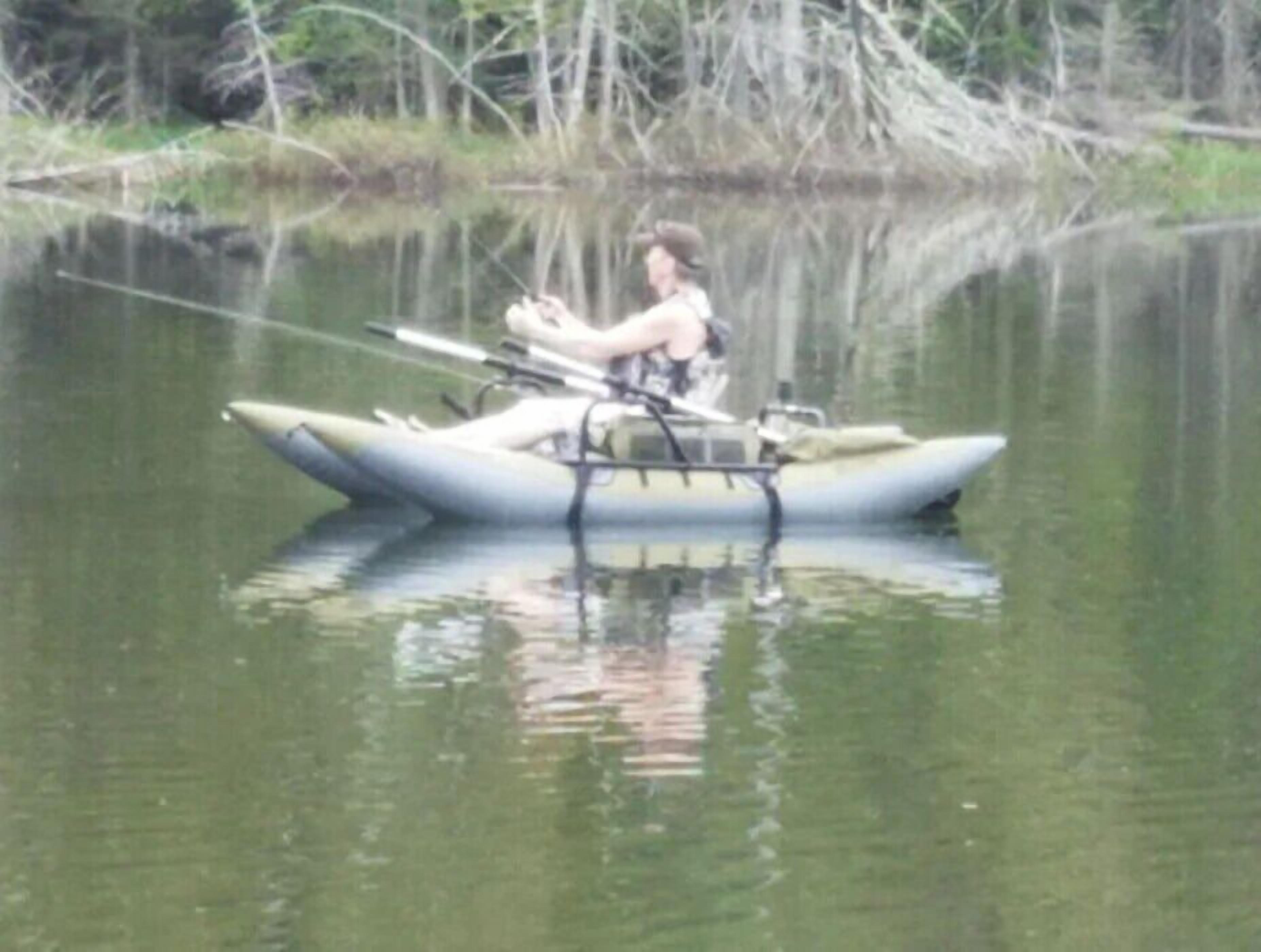 Una persona pescando desde un bote pequeño en aguas tranquilas.