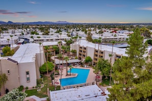 Relax by the central pool surrounded by lush greenery and palm trees.