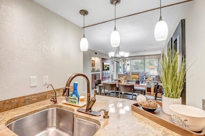 Enjoy meals in the well-lit kitchen with a stainless steel sink, marble countertop, and dining table for four.