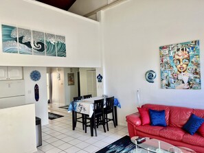 A dining area with a table set for four, a red leather sofa, and various wall art.