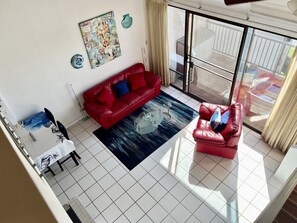 A living room with a red sofa, a glass coffee table, and a blue rug.