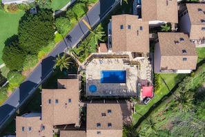 An aerial view of a residential area with multiple houses, a swimming pool, and a road.