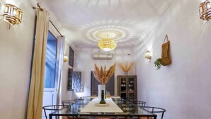 Zona pranzo con tavolo e sedie in vetro, un lampadario e un vaso decorativo.