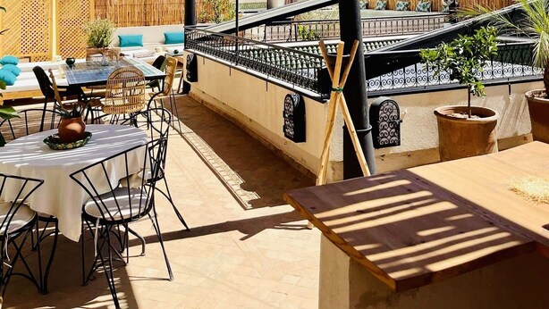 Una terrazza esterna con tetto di paglia, mobili in vimini e vista sulla città.