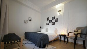 Una camera da letto con un letto, un comodino, una sedia e un tavolino con una lampada.