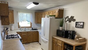 Una cocina moderna con armarios de madera, un refrigerador blanco, un microondas y una cafetera.