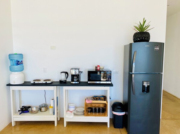 Une petite cuisine équipée d’un distributeur d’eau, d’une machine à café, d’un four à micro-ondes et d’un réfrigérateur.