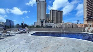 Area piscina sul tetto con poltrona prendisole e vista su alti edifici.