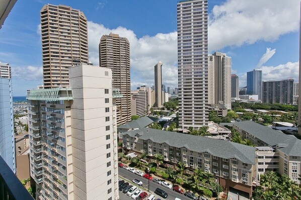 A high-rise residential building complex with multiple apartment buildings, a parking area, and a view of the city skyline. - Fully modernized 11th floor studio at The Palms (Honolulu)