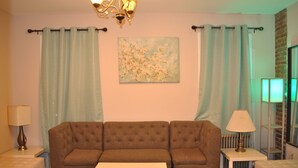 A living room with a brown sofa, a white coffee table, and a painting on the wall. - Motel Casa Downtown Guest House (Newark)