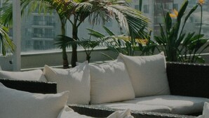 Un balcón con sofá, cojines y plantas en macetas.