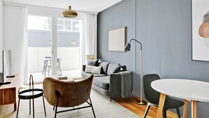 Una sala de estar moderna con un sofá gris, una mesa redonda de centro y una lámpara de pie.