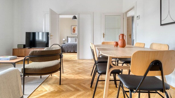 Una sala de estar moderna con televisor, sofá y mesa de comedor con sillas.