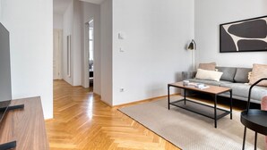 Un salon moderne avec un canapé gris, une table basse en bois et un lampadaire noir.