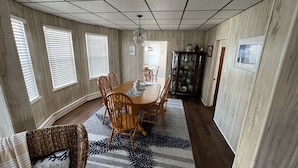 Une salle à manger avec une table en bois, des chaises, un tapis à motifs et un buffet aux portes vitrées.