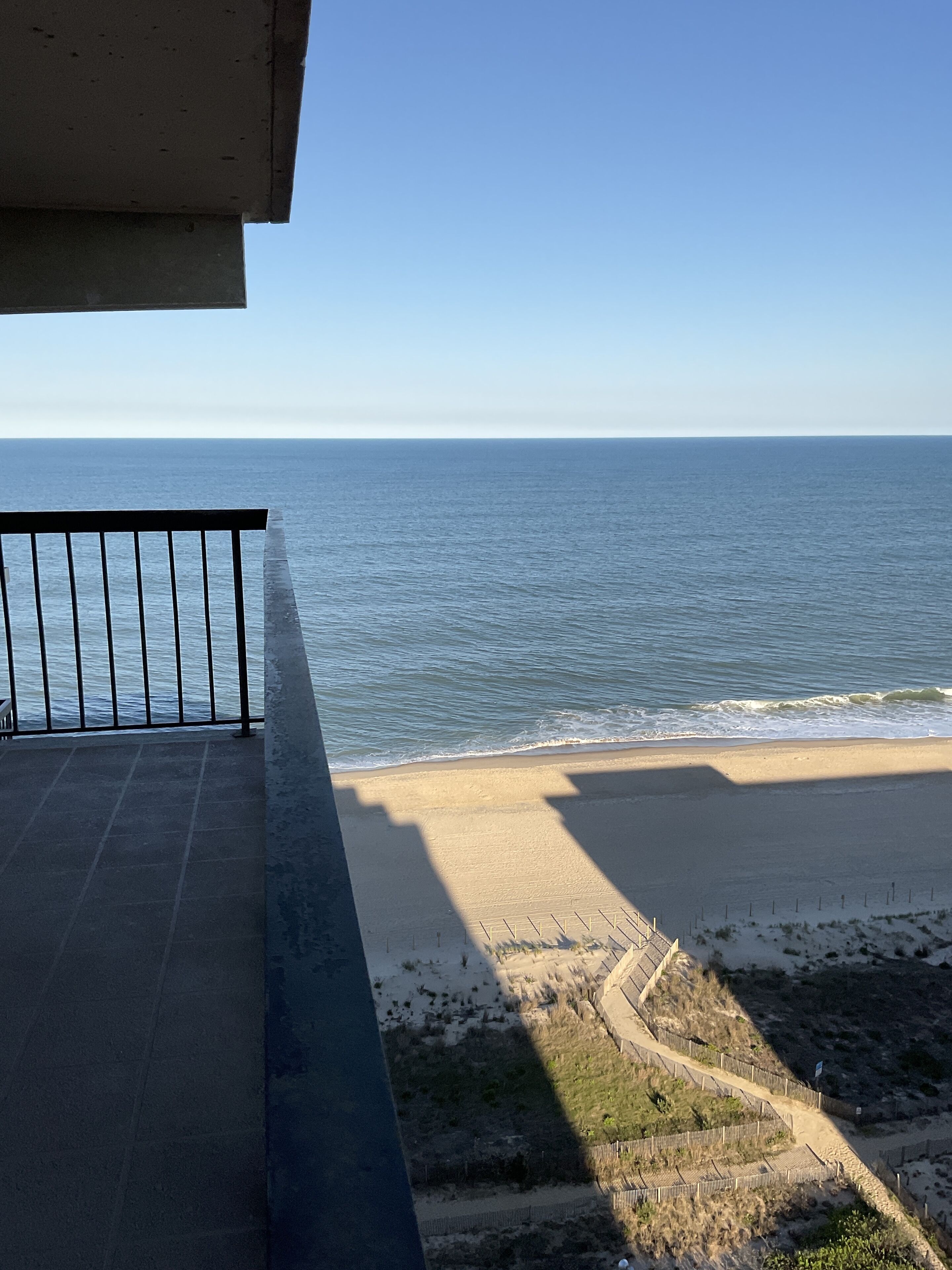Un balcón con vista a una playa de arena y al océano.