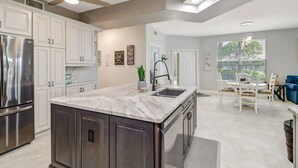 A modern kitchen with a large island, stainless steel appliances, and a dining area with a table and chairs. - 10118 Colonial Country Club Blvd #410 (Fort Myers)