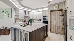 A modern kitchen with white cabinets, a marble island, and stainless steel appliances. - 10118 Colonial Country Club Blvd #410 (Fort Myers)