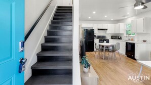 A modern kitchen with white cabinets, a black refrigerator, and a dining area with a white table and chairs. - Brookswood #A xxxxxx (Austin)