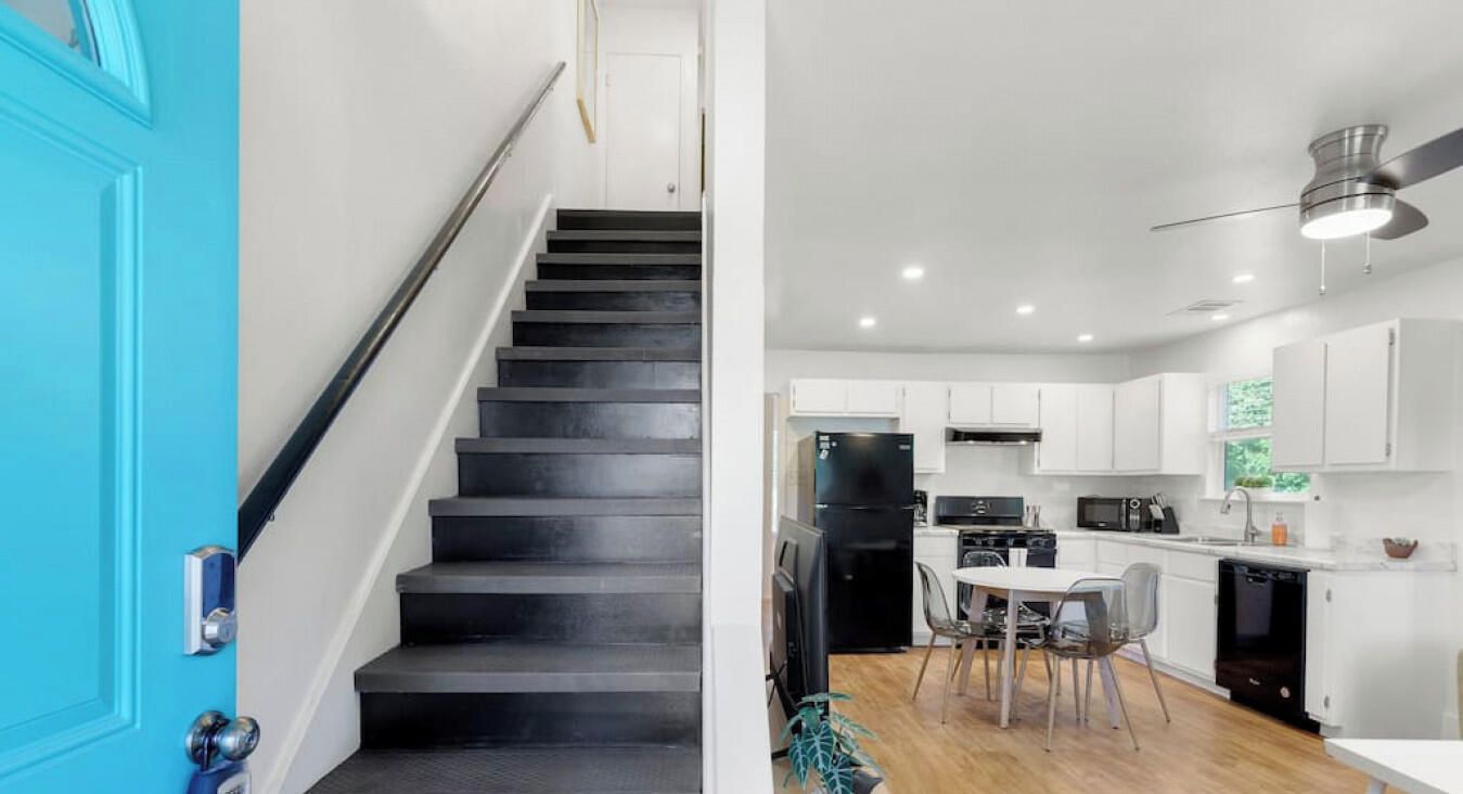 A modern kitchen with white cabinets, a black refrigerator, and a dining area with a table and chairs.
