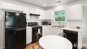 A modern kitchen with white cabinets, a black refrigerator, a stove, and a dishwasher. - Brookswood #A xxxxxx (Austin)
