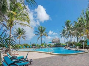 Relax by the pool surrounded by palm trees and lounge chairs.